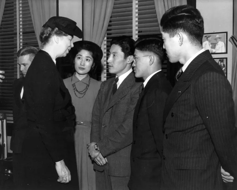 Black-and-white photograph of Eleanor Roosevelt speaking with four young Japanese American adults.