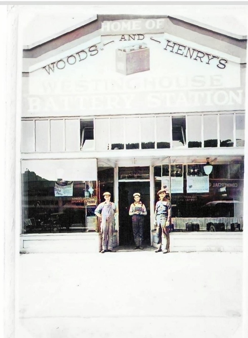 A colorized photo of three men, two of them Japanese American, in front of an auto garage.